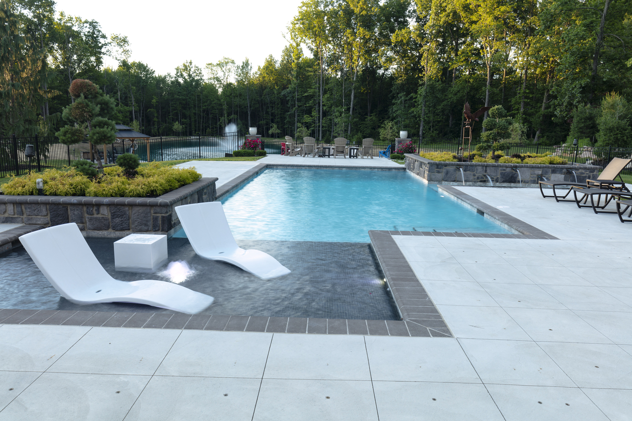 Rectangular swimming pool in front of a large fountain.