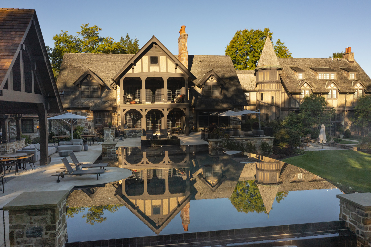 Side view of a freeform pool in front of a large residential property.