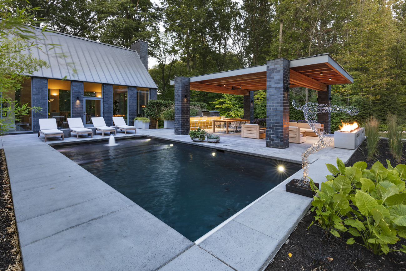 Small rectangular residential pool next to fire pit.