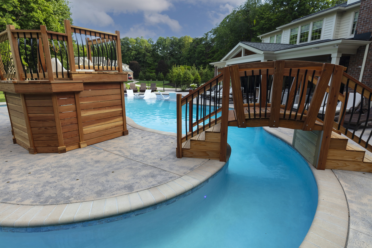 Freeform residential pool with real wood bridge and play area.