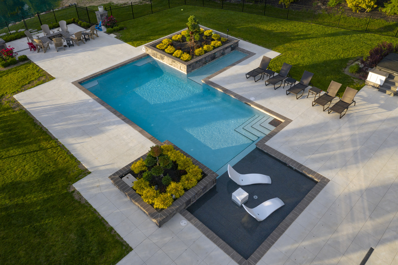 Geometric swimming pool installed with stone patio.