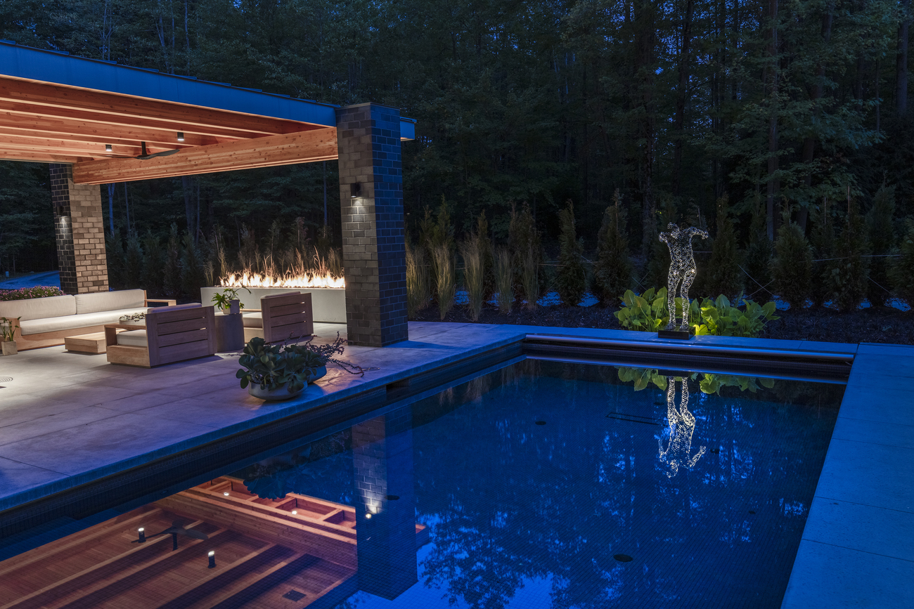 Geometric pool and statue of a man at night.