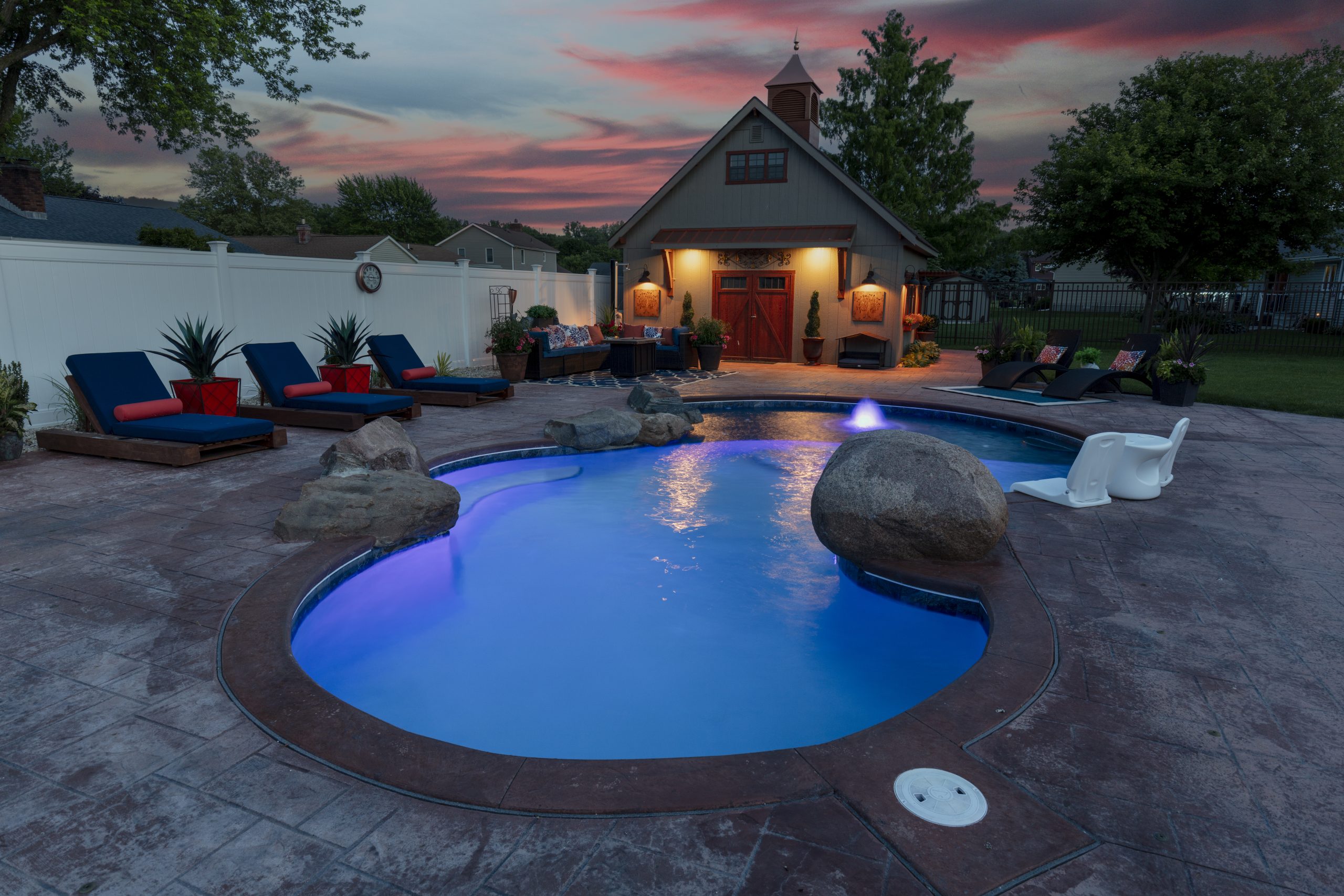a freeform pool with bubbler fountain with purple pool lighting