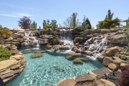 Freeform residential pool installed with natural stone fountains.