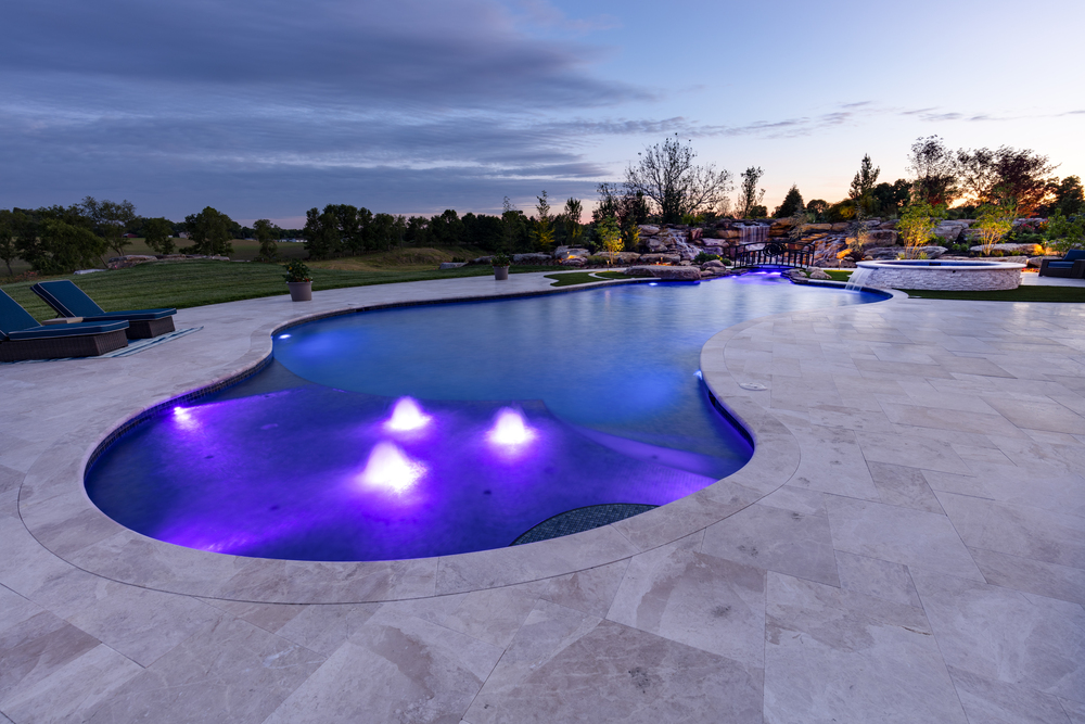 Residential freeform swimming pool with purple lights.