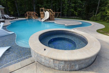 a raised custom spa next to family swimming pool