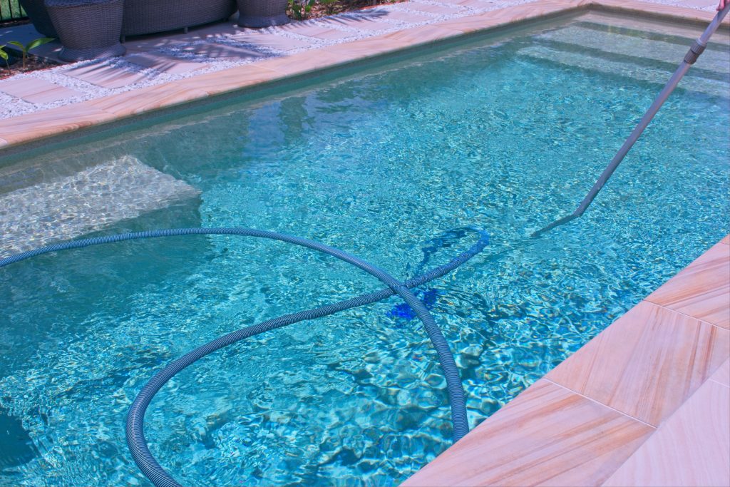 Pool cleaning vacuum and hose preparing for seasonal pool closing in Ohio.